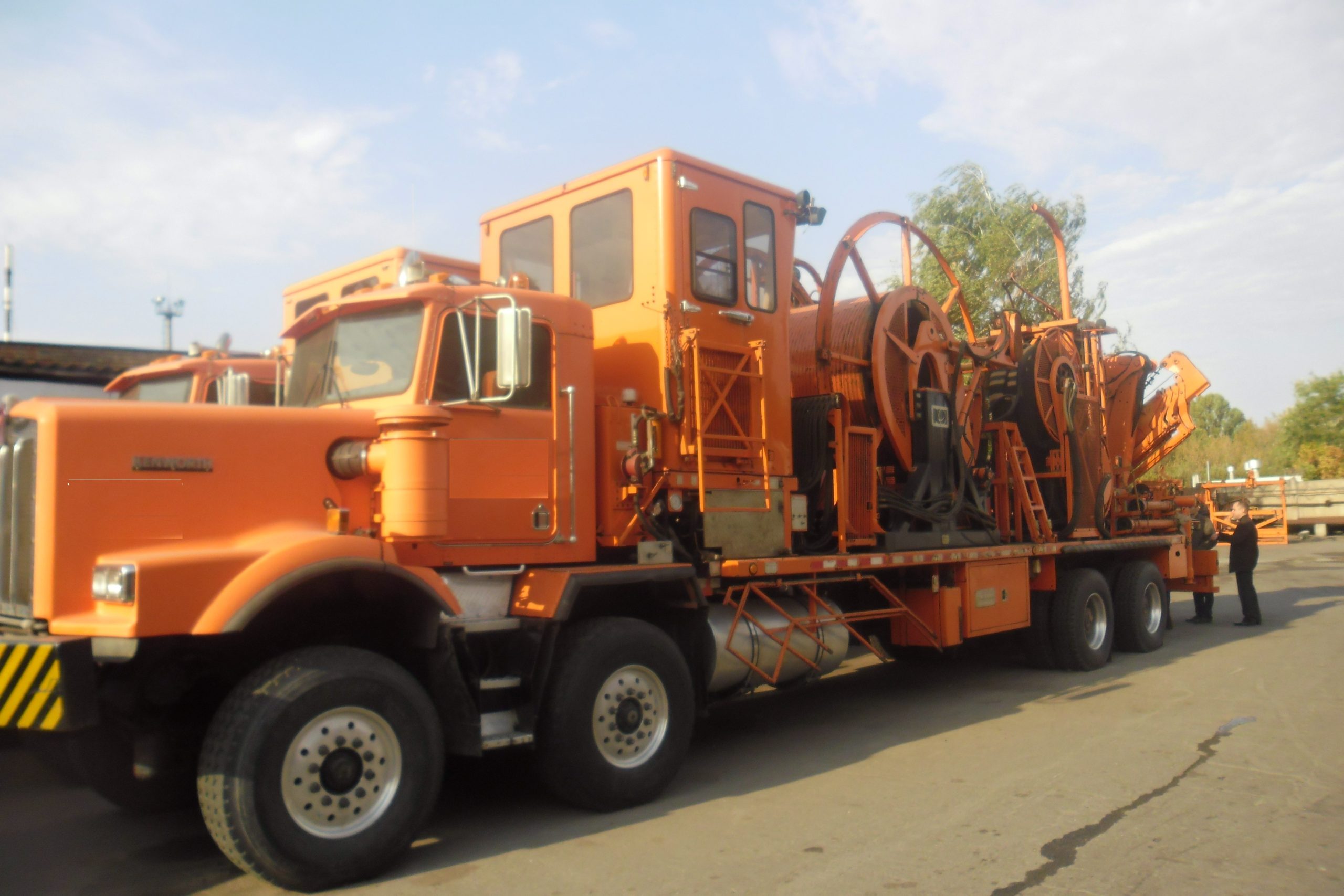Orange truck-mounted coiled-tubing unit with tubing reel and handling equipment.