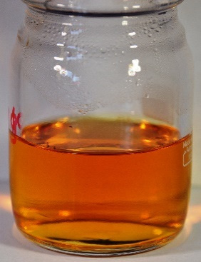 Orange acidizing-fluid sample in a glass bottle after laboratory heat exposure.