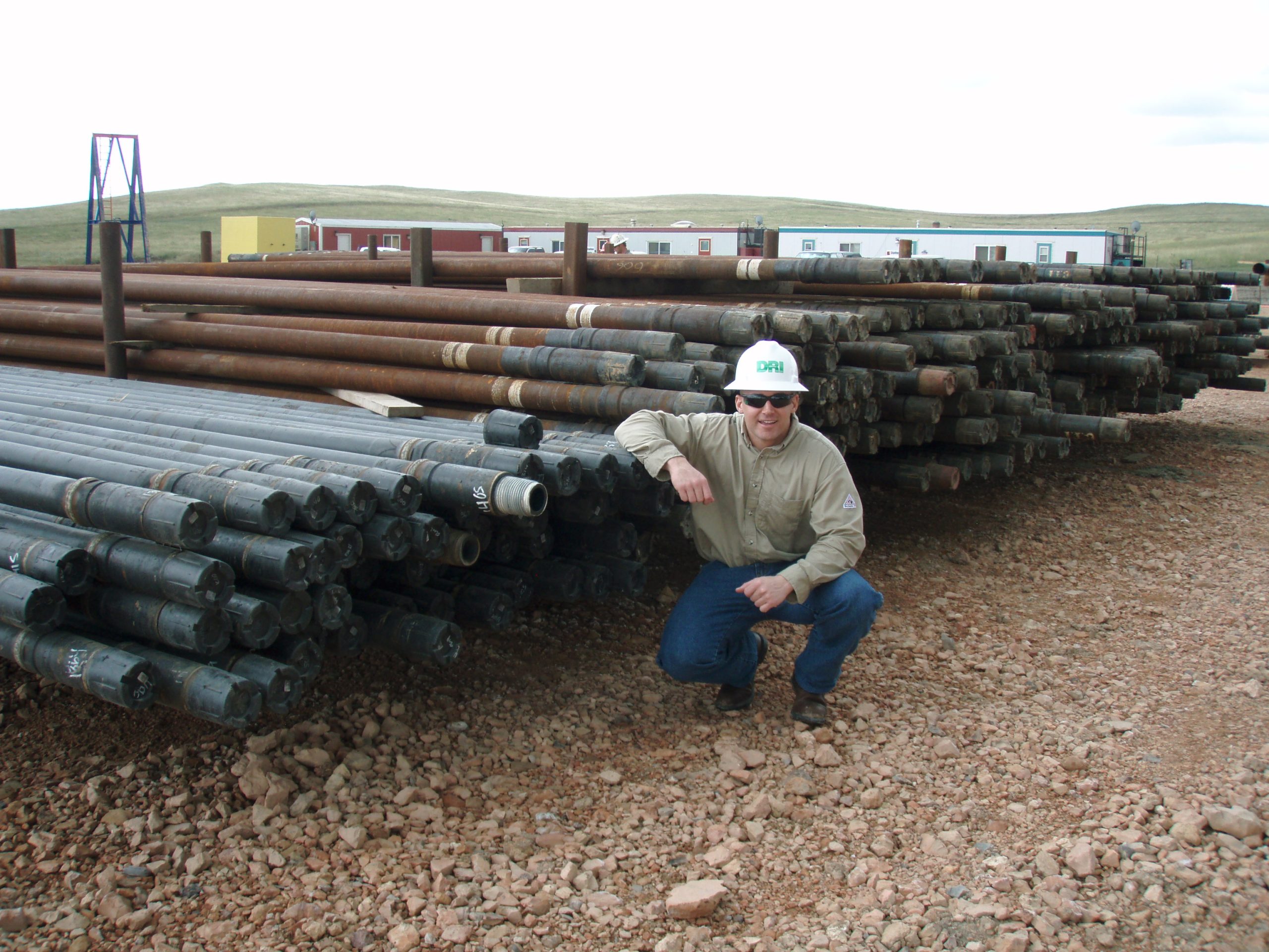 Drill pipe on storage racks, with enlarged tool joints and thread protectors visible.